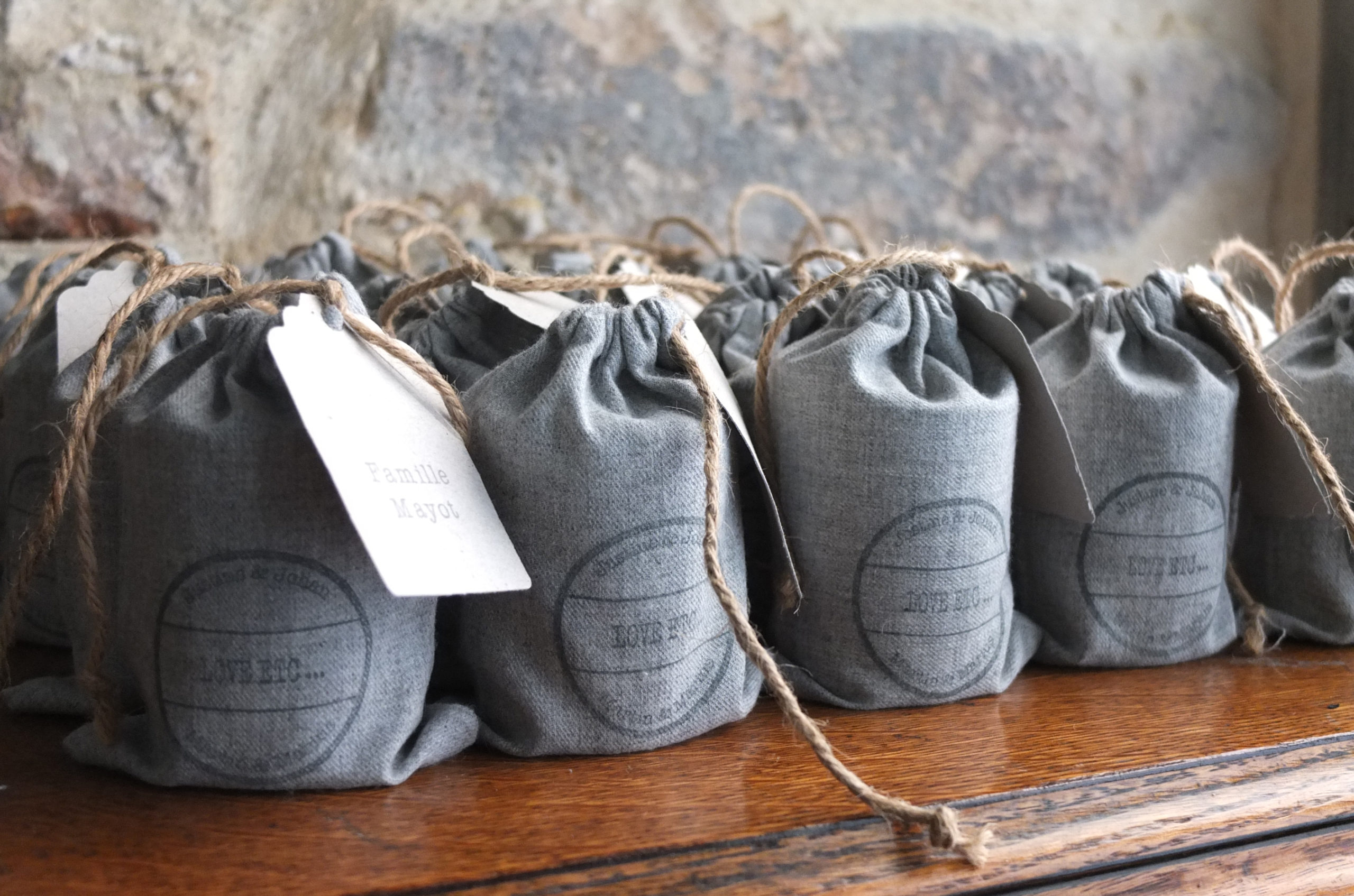 Pochons en flanelle grise pour un mariage d'hiver contenant une bougie artisanale les cadeaux pour les invités