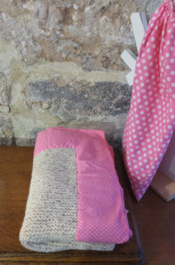 Couverture d'enfant tricotée à la main en laine beige et au contour en tissu rose à petits pois blancs